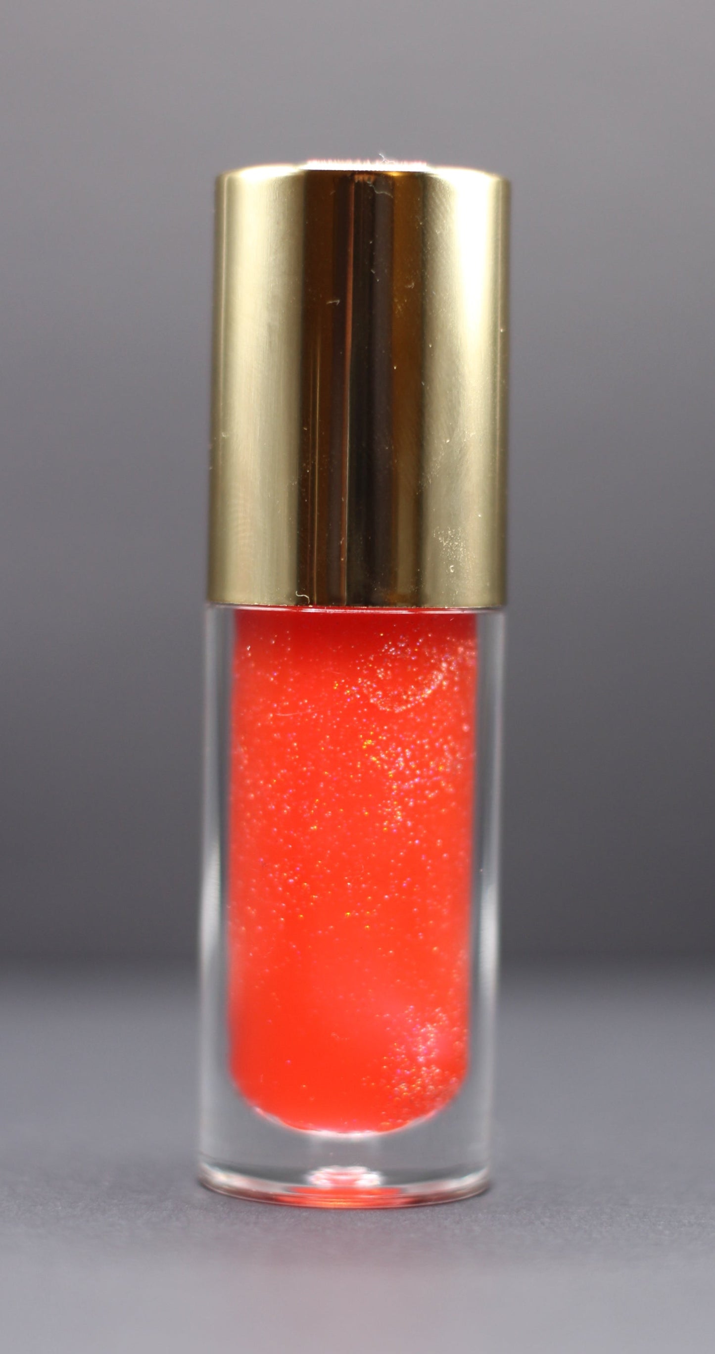 Holographic pink-red vegan lip oil with a fruity strawberry pineapple scent, lightweight with a high-gloss shimmer.