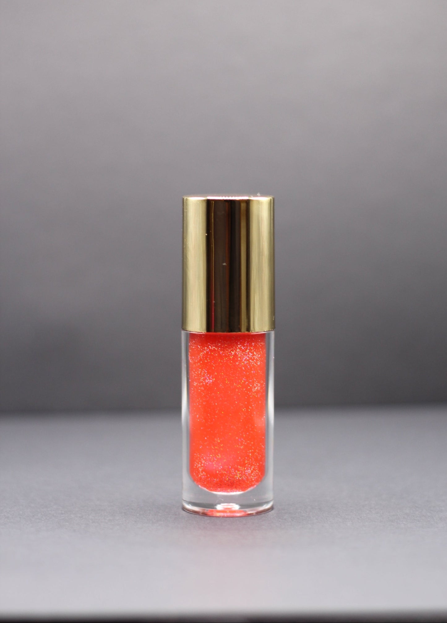 Holographic pink-red vegan lip oil with a fruity strawberry pineapple scent, lightweight with a high-gloss shimmer.