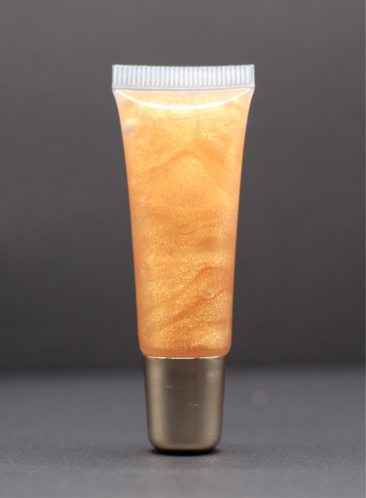 Warm gold shimmer vegan lip gloss with a strawberry scent, glossy and hydrating with a non-sticky feel for a soft golden finish.